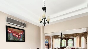 Un comedor con una gran mesa de madera rodeada de sillas ornamentadas, un candelabro y un cuadro en la pared.