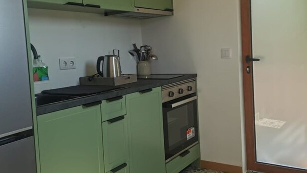 A compact kitchen with green cabinets, a stove, and a sink. - Private Pool With Huge Terrace Garden (Celorico de Basto)