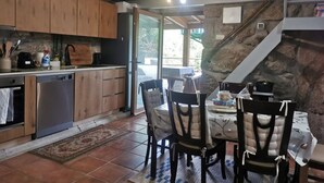 A kitchen with wooden cabinets, a dishwasher, and a dining area with chairs and a table. - Private Pool With Huge Terrace Garden (Celorico de Basto)