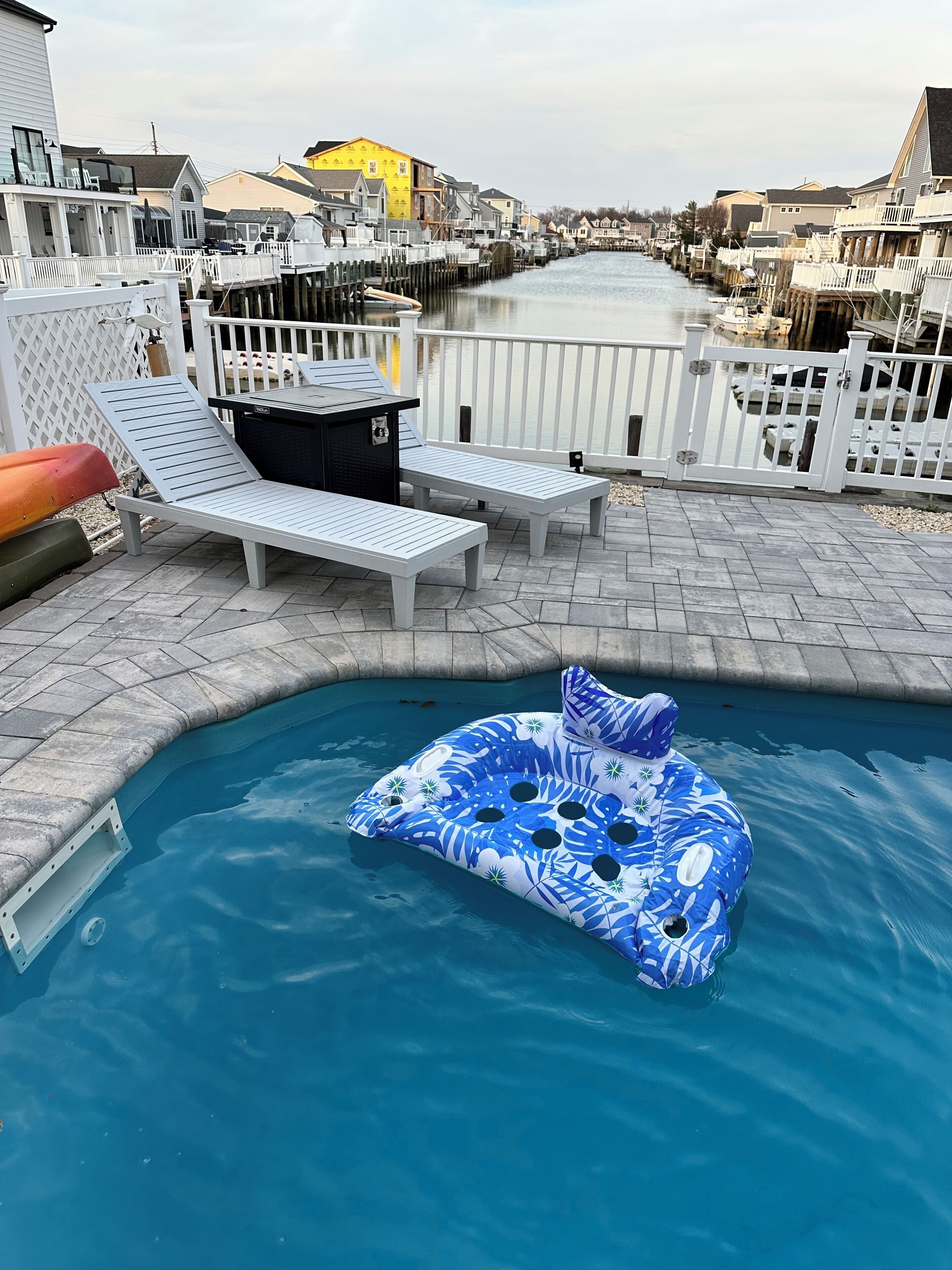 A pool area with lounge chairs and an inflatable pool float.