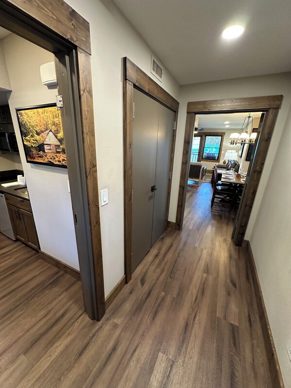 A hallway with wooden flooring, a dining area with a table and chairs, and a kitchen area with cabinets and a refrigerator. - Cozy 2-bedroom condo with AC in awesome Gatlinburg (Gatlinburg)