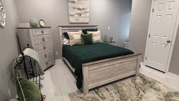 Un dormitorio con cama, cómoda, silla y ventilador de techo.