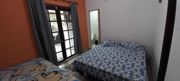 Une chambre à coucher avec un lit, une fenêtre avec des rideaux et une porte donnant sur une salle de bain.