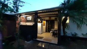 Une maison moderne dotée d’une cuisine et d’un espace repas à aire ouverte, d’un réfrigérateur visible et d’un petit coin salon extérieur.