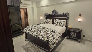 A bedroom with a bed, bedside tables, a ceiling fan, and an air conditioning unit. - Karachi Beach Residency (Karachi)