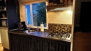 Una cucina con piano cottura a gas, lavello, finestra e macchina da caffè.