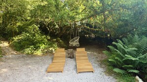 A wooden deck with a hanging chair and a swing, surrounded by dense greenery. - L'Autre Paradis, Natural Pools, Beaches, Enchanted Garden, Sauna (Poligny)