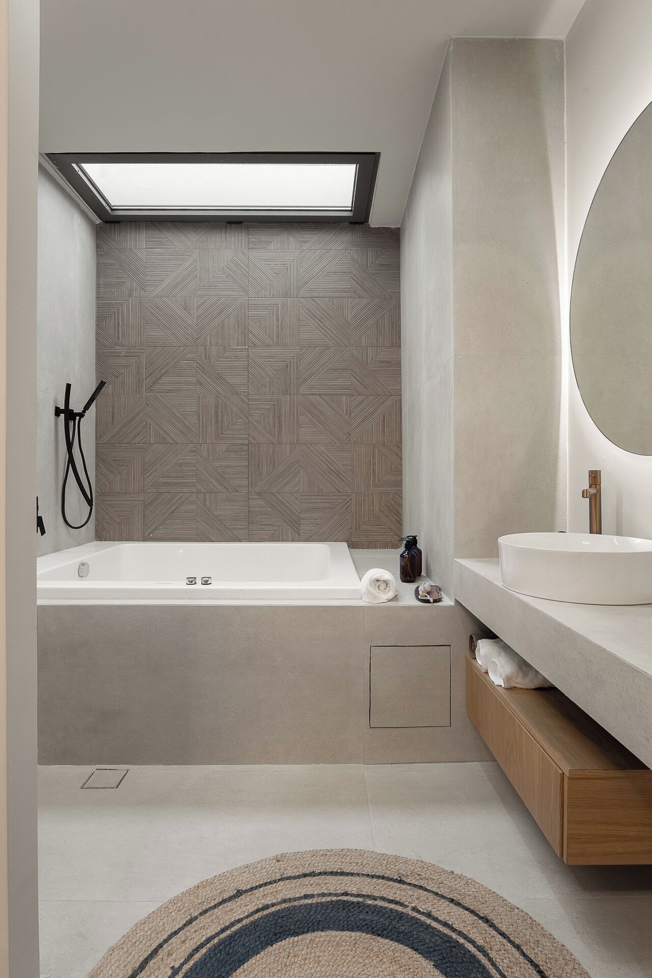 Ein modernes Badezimmer mit einer freistehenden Badewanne, einem großen Spiegel und einer Wand mit Muster.