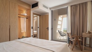 Una habitación de hotel moderna con una cama grande, un escritorio con una silla y un ventanal corredero que da a un balcón.