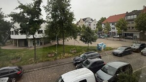 A parking area with several cars, including a white van, and a row of buildings with a mix of architectural styles. - Studio 2 beds Kitchen BAD TV Wlan (Bremen)