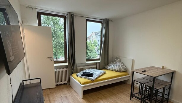 A bedroom with a bed, a desk, a chair, a radiator, and a TV. - Studio 2 beds Kitchen BAD TV Wlan (Bremen)
