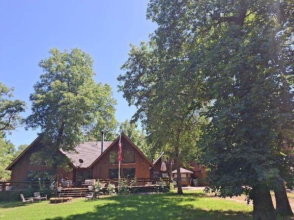 Un chalet rustique doté d’une cheminée imposante, d’un mât pour drapeau et d’une pelouse bien entretenue.