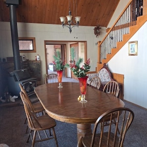 Un coin repas avec une table et des chaises en bois, une cheminée et un escalier.