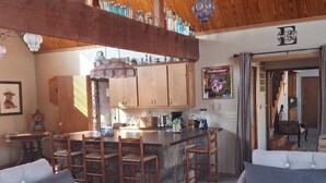 Un intérieur chaleureux avec un coin bar, un plafond en bois et une cuisine dotée de meubles en bois.