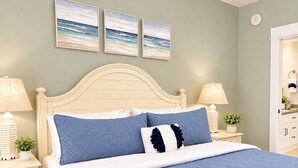 Un dormitorio con cama, dos mesitas de noche, una lámpara, un estante en la pared y una puerta.