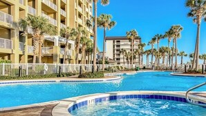 Un hotel con piscina, palmeras y un cielo azul despejado.