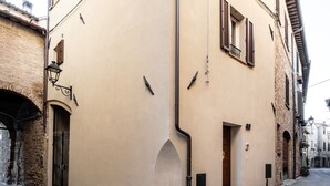 Une rue étroite, bordée d’un immeuble dont la façade est ornée d’une porte en bois et d’une petite fenêtre avec des volets.