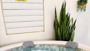 A hot tub with two built-in seats, surrounded by a white wall and a potted plant. - Casita Blue Surfer-Luquillo 15 minutes to El Yunque, and 3 minutes to the beach (Luquillo)