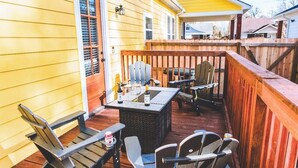 A wooden deck with a table and chairs, a bottle of wine, and a can of soda. - Family-Friendly Free Parking, Drinks & Snacks all complementary (Memphis)
