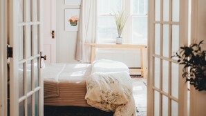 Une chambre à coucher avec un lit, une table de chevet, une fenêtre et une porte.