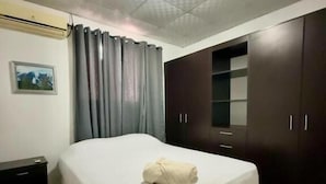 Un dormitorio con cama, armario de madera oscura y una mesita de noche.