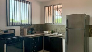 Una cocina compacta con estufa, horno y refrigerador.