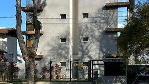 Un bâtiment moderne à la façade plate, doté de nombreuses fenêtres et d’une entrée protégée par un portail.