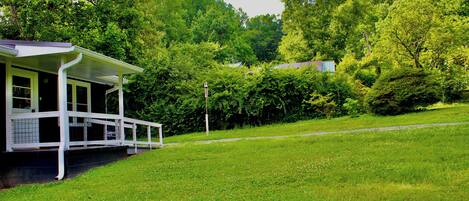 A house with a porch, surrounded by lush green trees and grass.