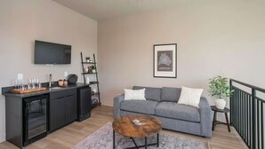 Un salon moderne avec un canapé gris, une table basse, un téléviseur fixé au mur et un ventilateur de plafond.