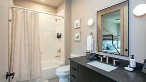 Une salle de bain moderne équipée d’une douche, de toilettes et d’un meuble-lavabo.
