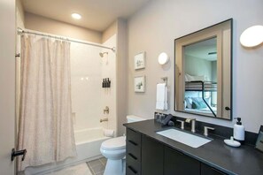 A modern bathroom with a shower, toilet, and vanity. - 2 Bedroom + Loft Condo, Coffee Shop in Building (Nashville)