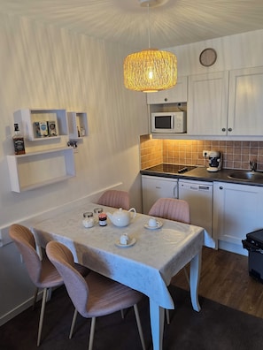 A compact kitchen with white cabinets, a microwave, a coffee maker, and a dining table with chairs. - Apartment with kitchenette in the mountains of Valmeinier  (Valmeinier)