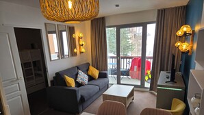 A modern hotel room with a sofa, dining table, chairs, a small kitchen area, and a balcony with outdoor furniture. - Apartment with kitchenette in the mountains of Valmeinier  (Valmeinier)