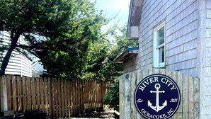 Een houten hek met een bord waarop staat 'River City Ocracoke, NC' en het jaar 2025.