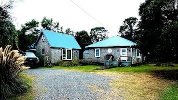 A two-story building with a blue roof, a front porch, and a gravel driveway.