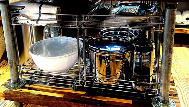 Een keuken met een inbouwfornuis, een spoelbak en houten kastjes.