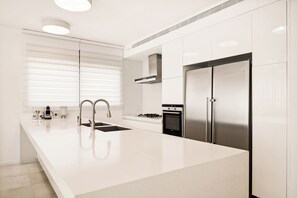 A modern kitchen with white cabinetry, a stainless steel refrigerator, a gas stove, and a built-in oven. - Insane 5BR Luxe Penthouse with Jacuzzi by the Shuk (Jerusalem)