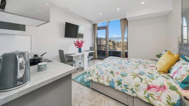 Une chambre d’hôtel moderne équipée d’un lit, d’un bureau, d’une télévision à écran plat et d’un balcon avec vue.