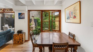 Un comedor con una mesa y sillas de madera, un sofá azul, una radio antigua y un cuadro en la pared.