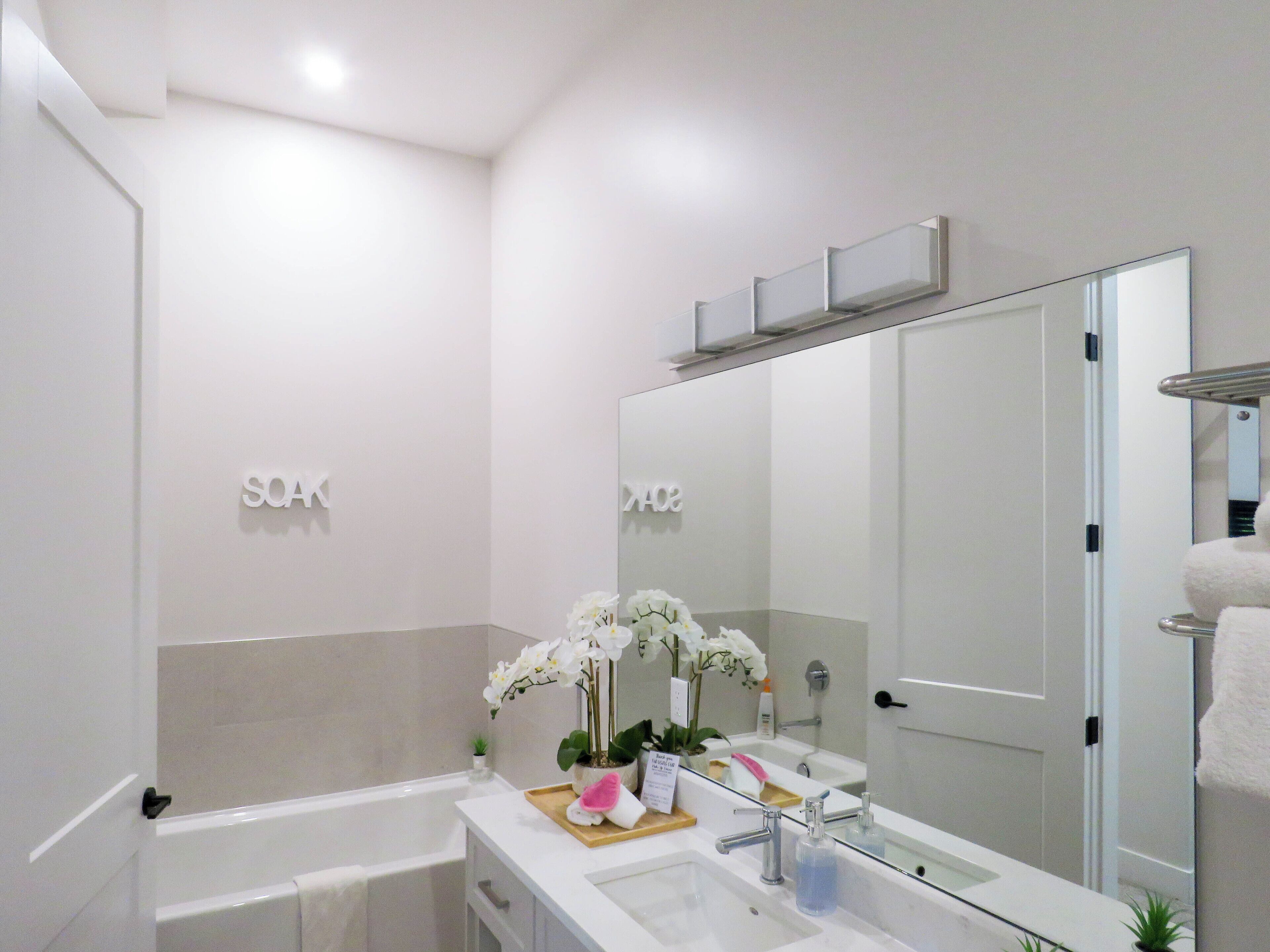 A modern bathroom with a white sink, a large mirror, and a bathtub.