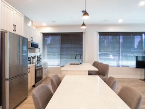 Una cocina moderna con una isla central, electrodomésticos de acero inoxidable y una zona de comedor con sillas.
