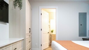 Une chambre à coucher comprenant un lit, une commode et une porte donnant sur une salle de bain.