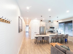 A modern kitchen with white cabinets, stainless steel appliances, and a central island with bar stools. - Beach Suites Parksville (Parksville)