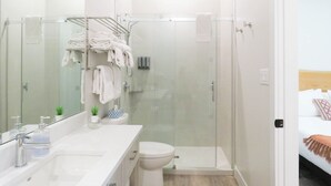 Une salle de bain moderne avec une douche à parois de verre, un lavabo blanc avec un miroir et des toilettes.