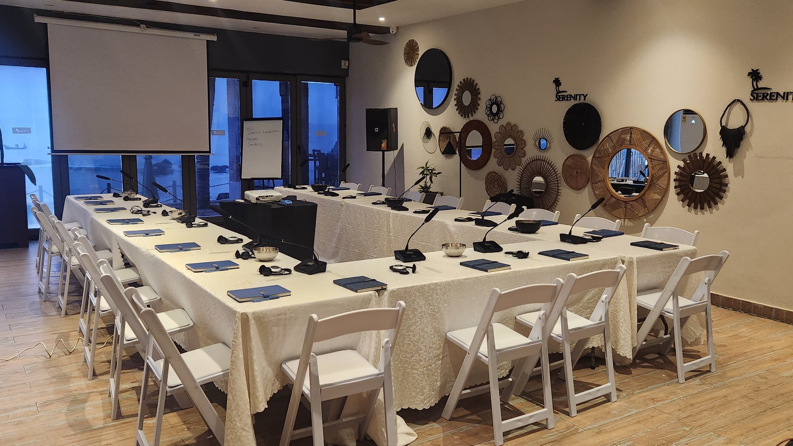Una sala de conferencias con una larga mesa, sillas blancas y una pizarra.