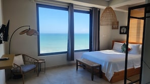 A bedroom with a large window, a bed, a chair, a desk, and a hanging light fixture. - Serenity Beach Annex (Kokrobite)