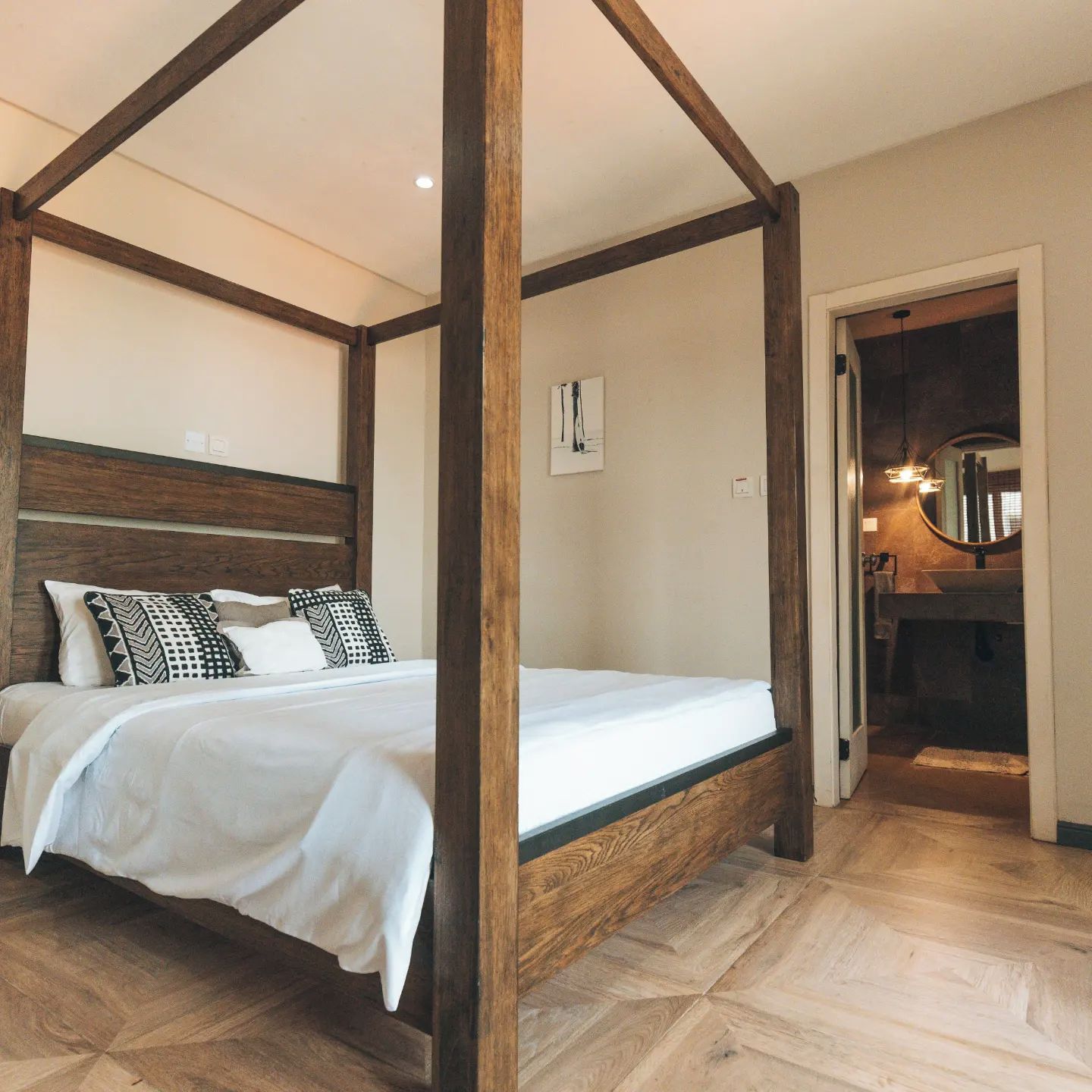 A four-poster bed with a wooden headboard, white bedding, and patterned pillows.