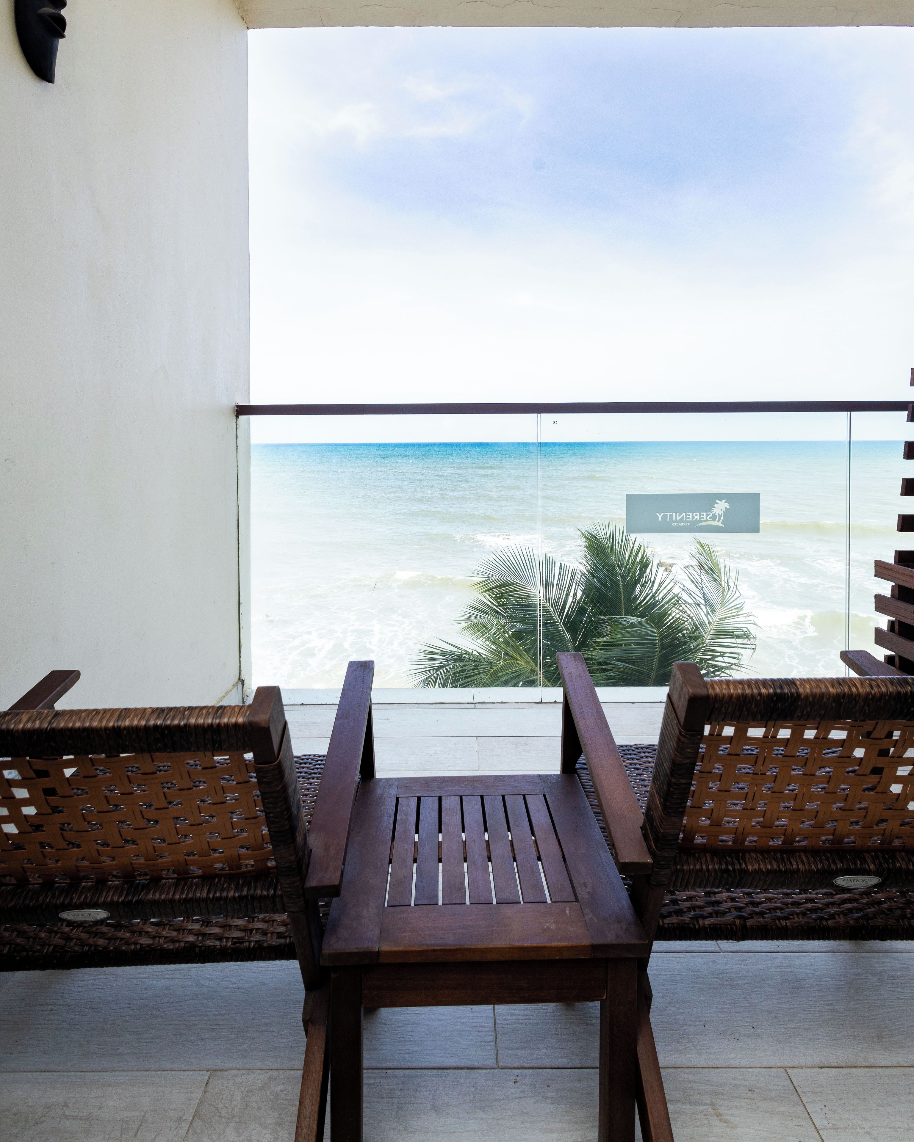 Ein Balkon mit zwei Holzstühlen und Blick auf das Meer.