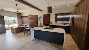 A modern kitchen with a central island, wooden cabinets, and a dining area with a ceiling fan.