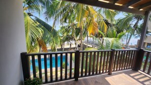 A balcony with a view of a pool and palm trees.